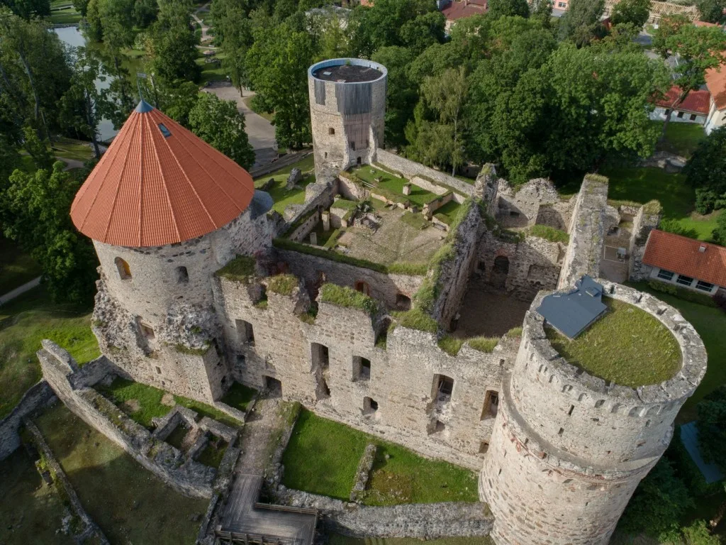 An aerial view of Cēsis Medieval Castle, its stone towers and surrounding park